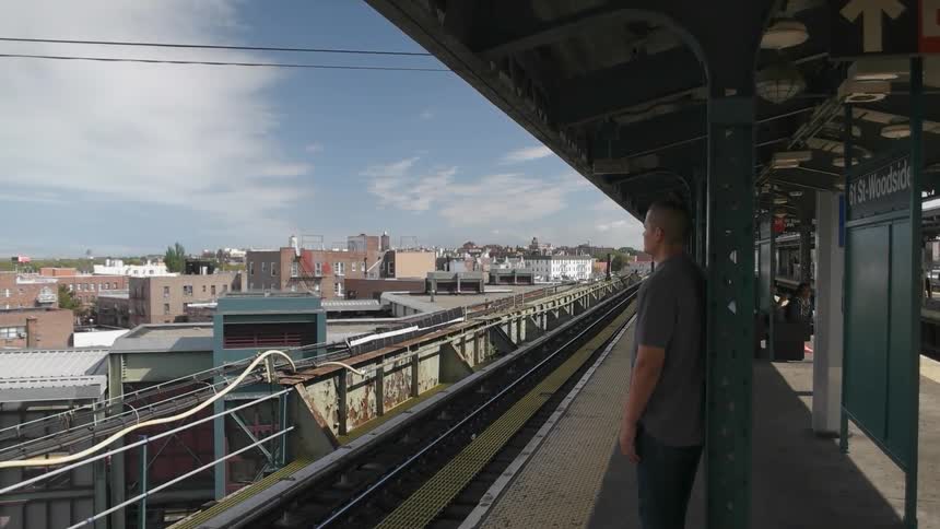 A man is standing at a commuter rail station during the day