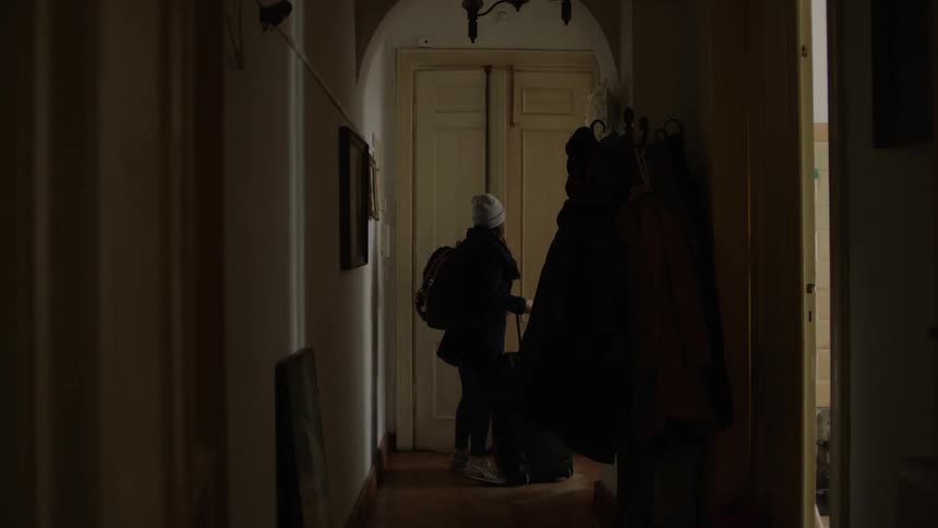 A woman enters a home with a suitcase in hand