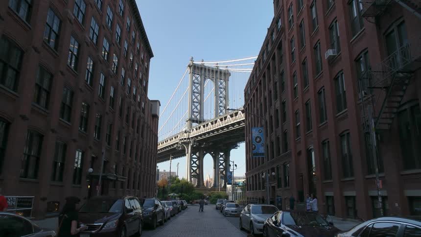 Traffic travels over a bridge at the end of a city street