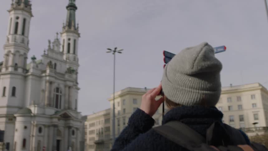A woman takes a photograph of a city building