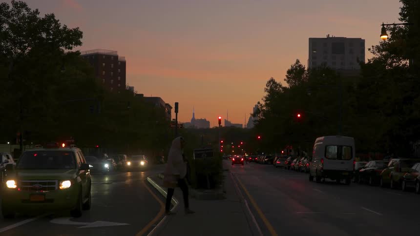 Person walks across a busy street at sunset