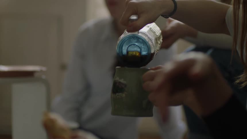 A woman pours coffee into a mug