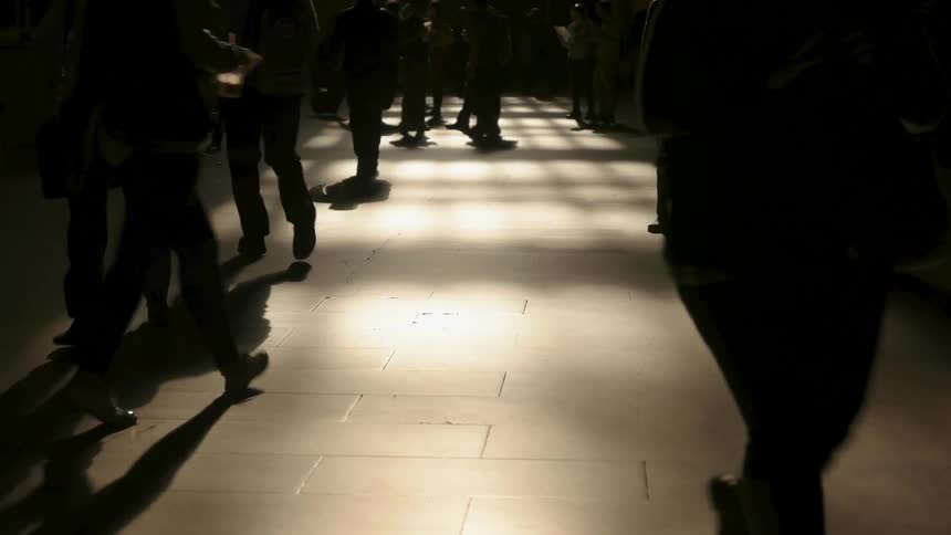Commuters walk across a floor