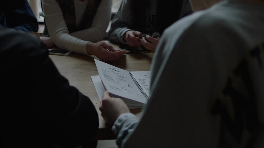 A group of women sit around a table with a notebook