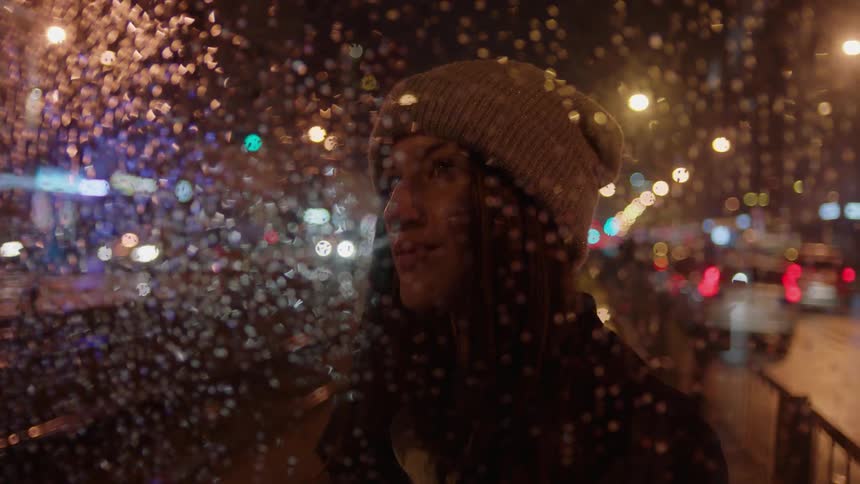 A woman looks through a wet window
