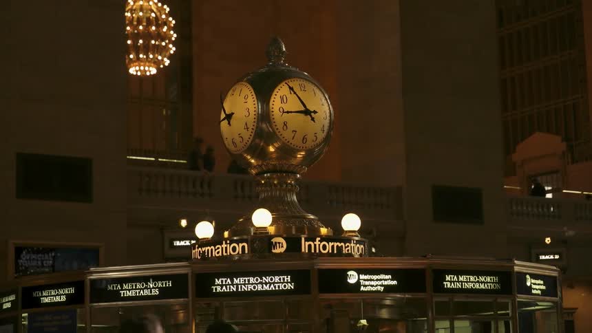 A large clock stands atop a ticket terminal