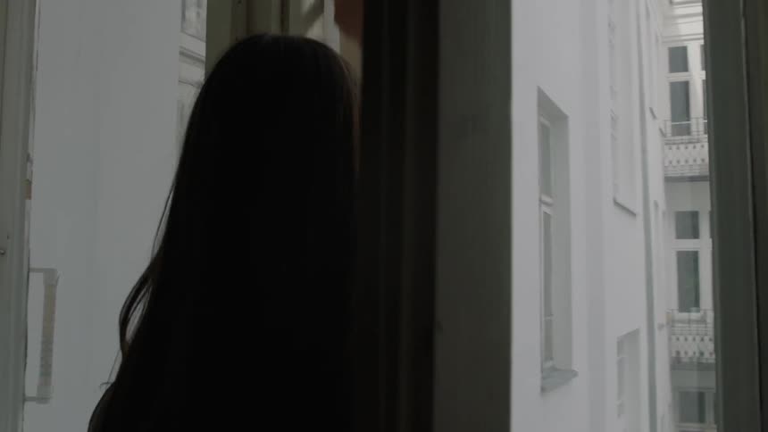 A woman opens up the apartment window