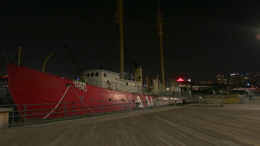 Large red ship parked in a harbor near a boardwalk