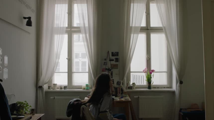 A girl stands up from a chair in a bedroom