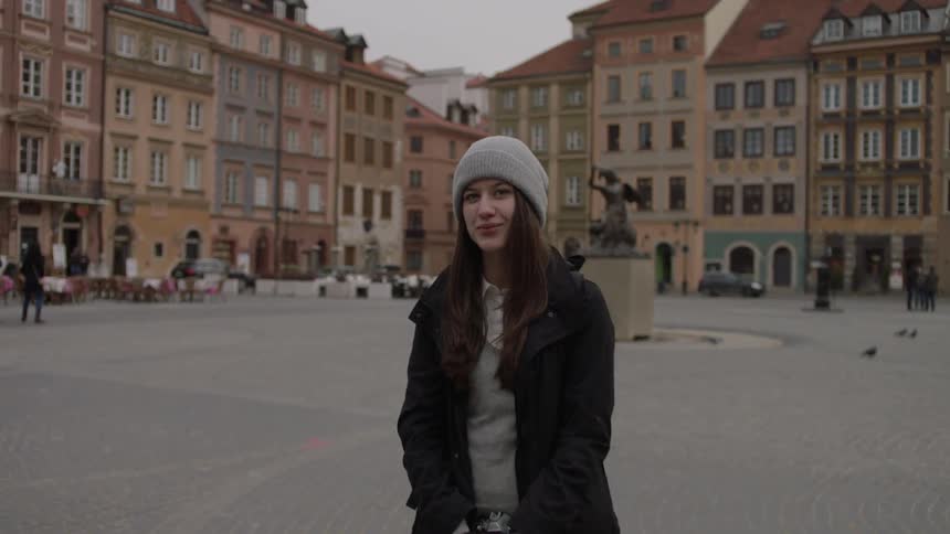 Woman smiling and standing in a city square