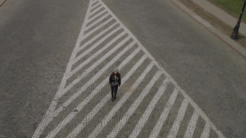 A woman walks down the middle of a street
