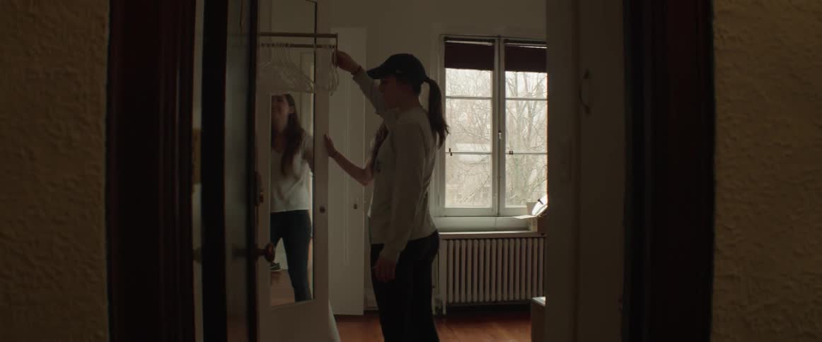 Two women look in a closet and one pulls out a rack