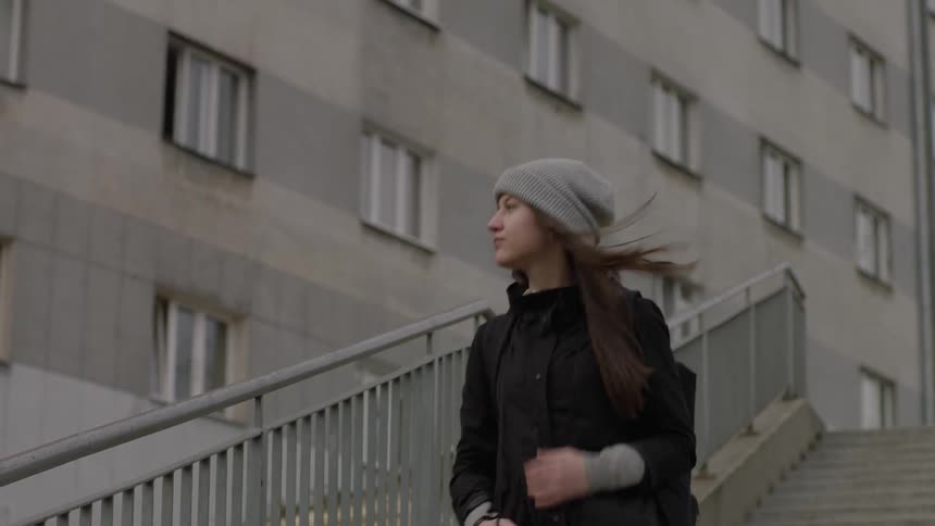 Woman walks down stairs outside on a windy day