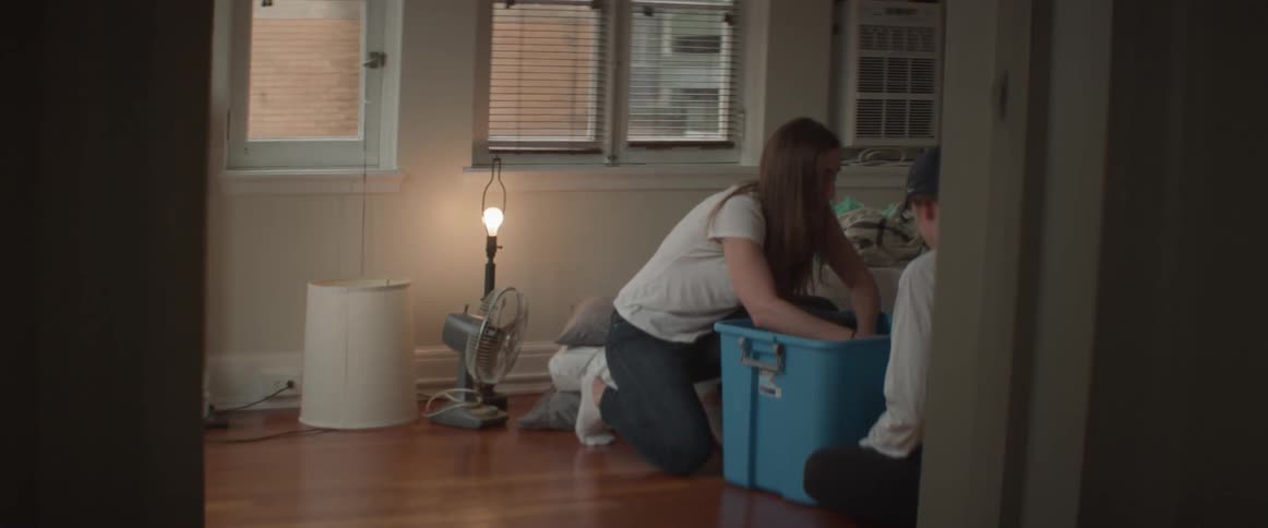 Two women are packing a container with household items
