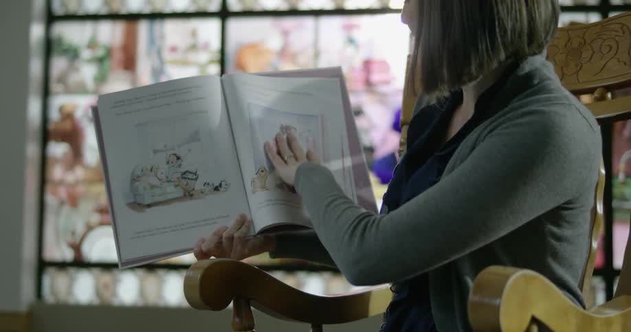 A woman reads a book to children