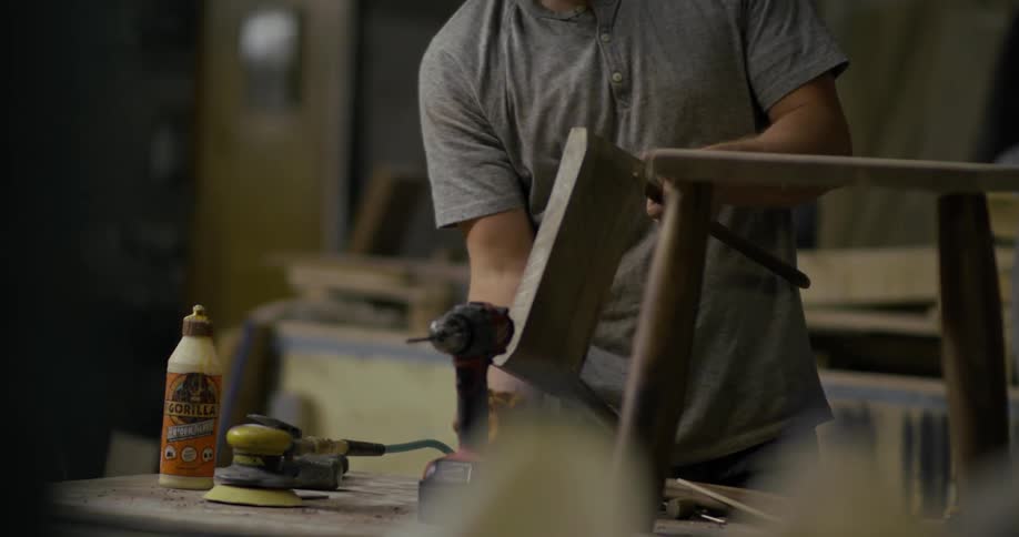 A man wipes a piece of wood with a rag