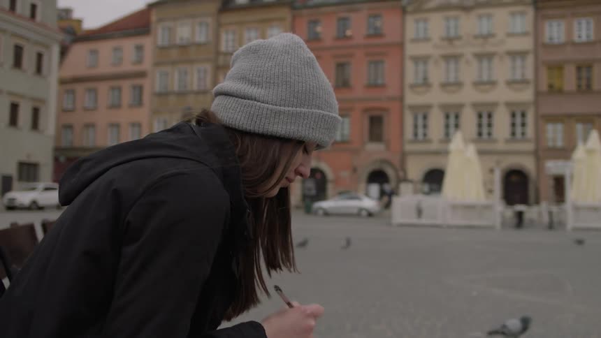 A woman writes in a journal on a city bench