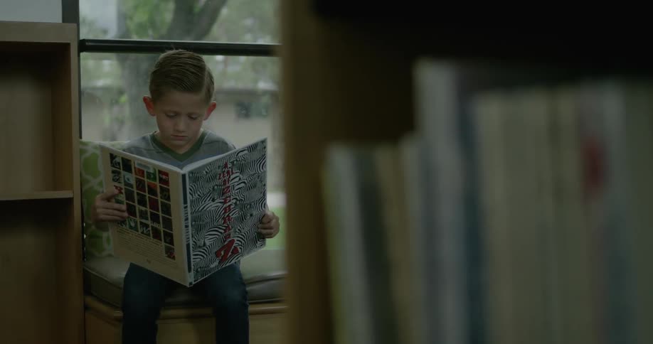 A boy is sitting down reading a book