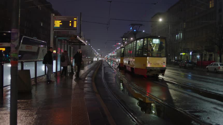 Public transportation moving through a large city on a wet evening