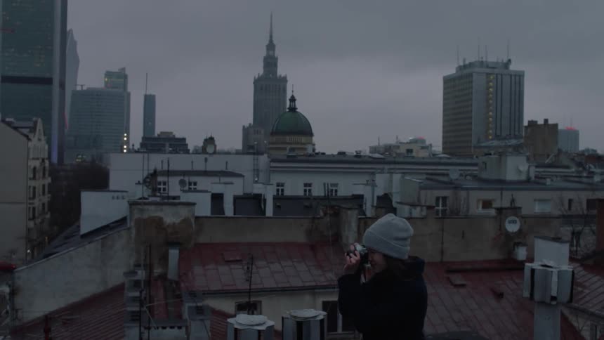 A woman takes a photograph in a city