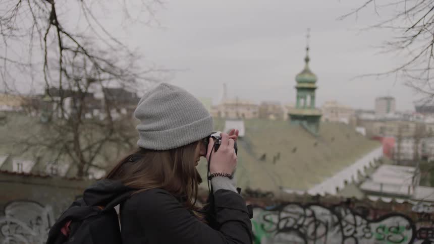 A woman takes photos of an urban view during the day