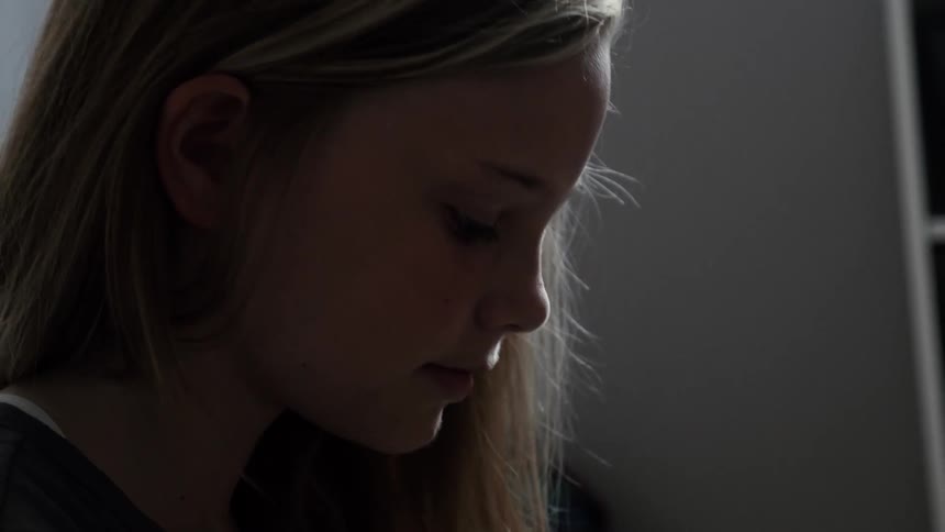 Blond girl looking down at something indoors