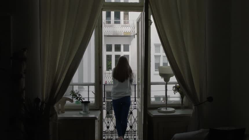 A woman stands on her balcony looking over