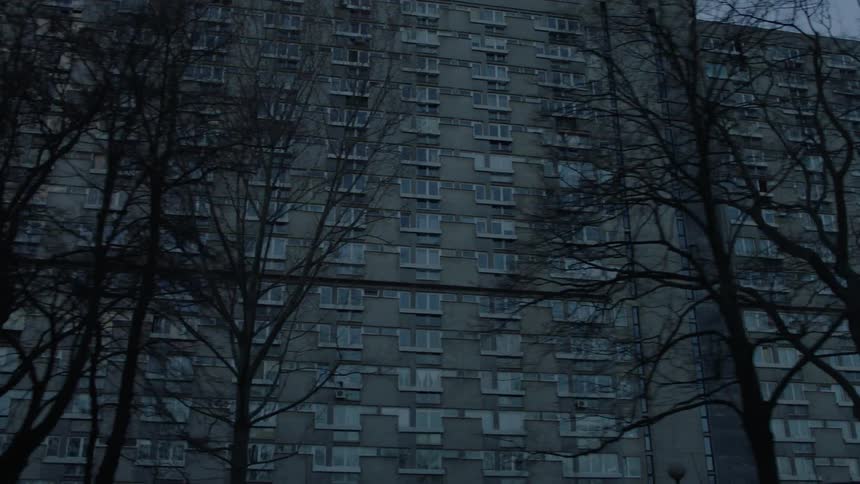 Large building with many windows sits next to some trees