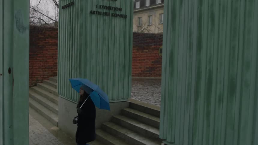 A woman walks down stairs with a blue umbrella