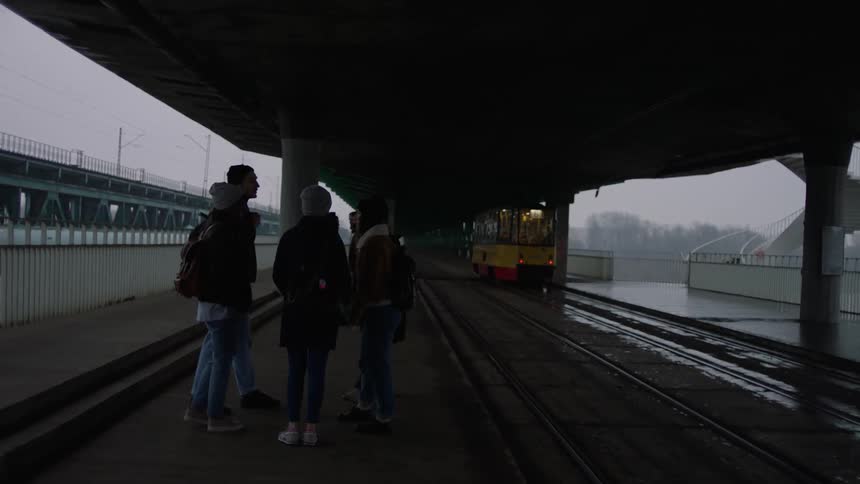 People wait at a train station on a rainy day