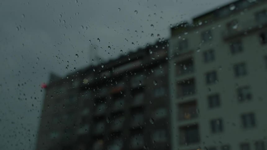 View looking out of a rain spattered window at buildings
