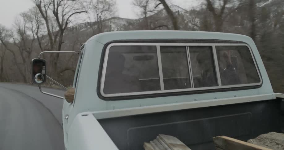 Two men ride in a truck on a mountain road