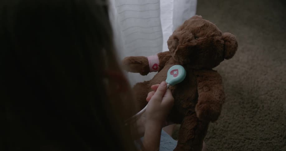 Child plays doctor with a stuffed bear
