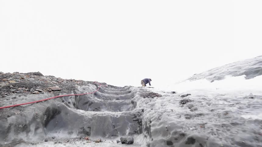 A hiker climbs up an icy mountain