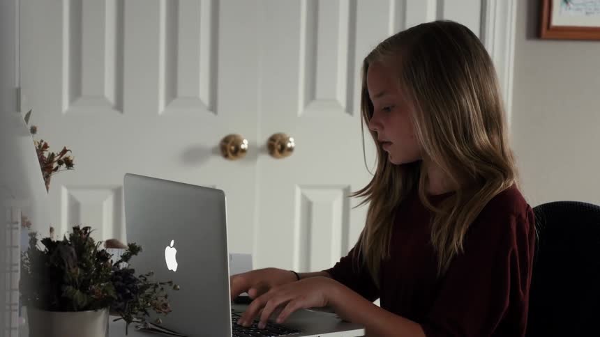 Young girl types on her laptop computer