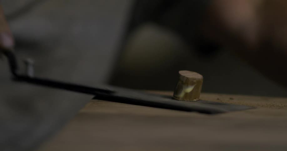 Person uses a tool to saw a piece of wood off