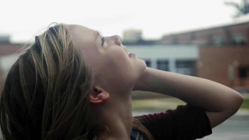 A girl with blond hair looks up at the sky