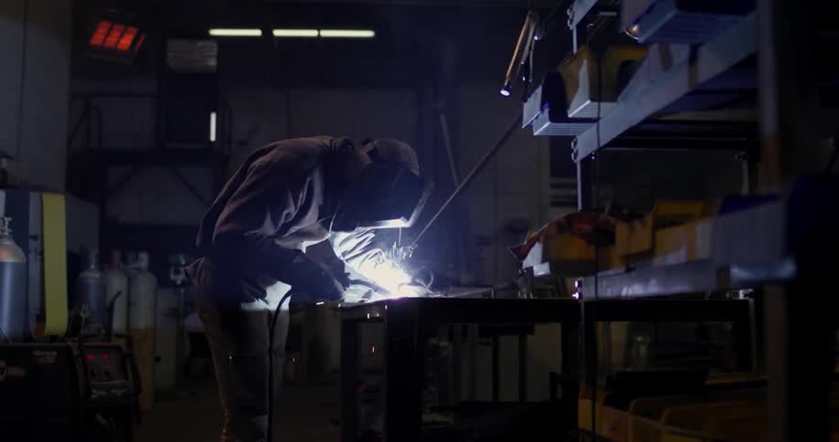 A man is using a welding tool in a workshop