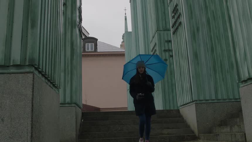 A woman walks in a city with an umbrella
