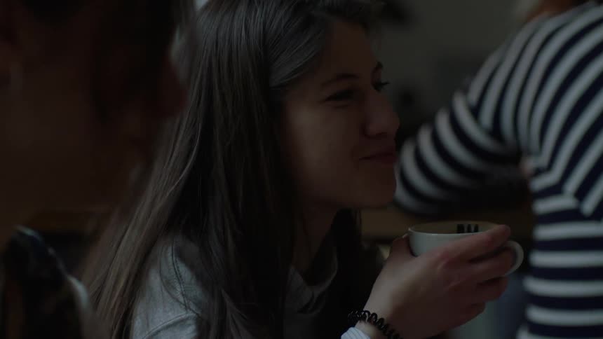 A girl drinks coffee and talks with friends