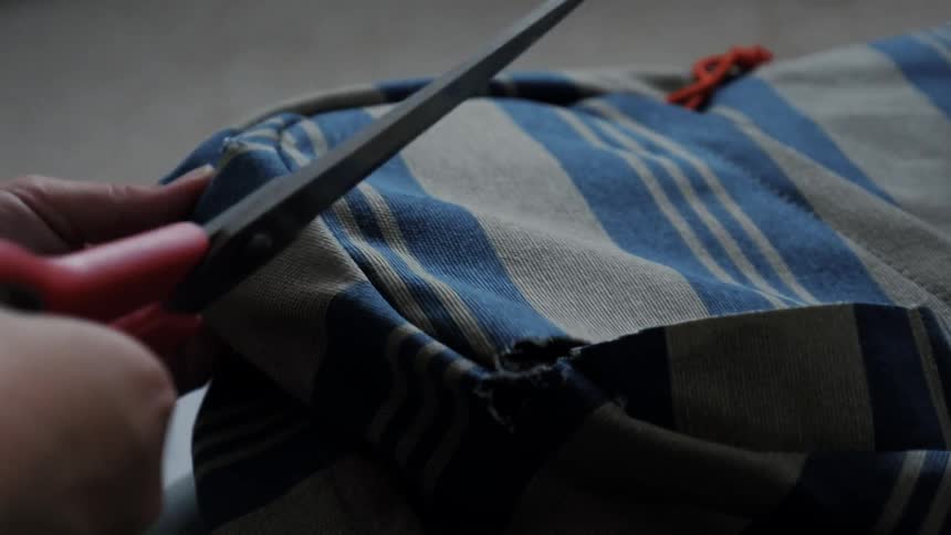 Person cuts a piece of cloth with scissors