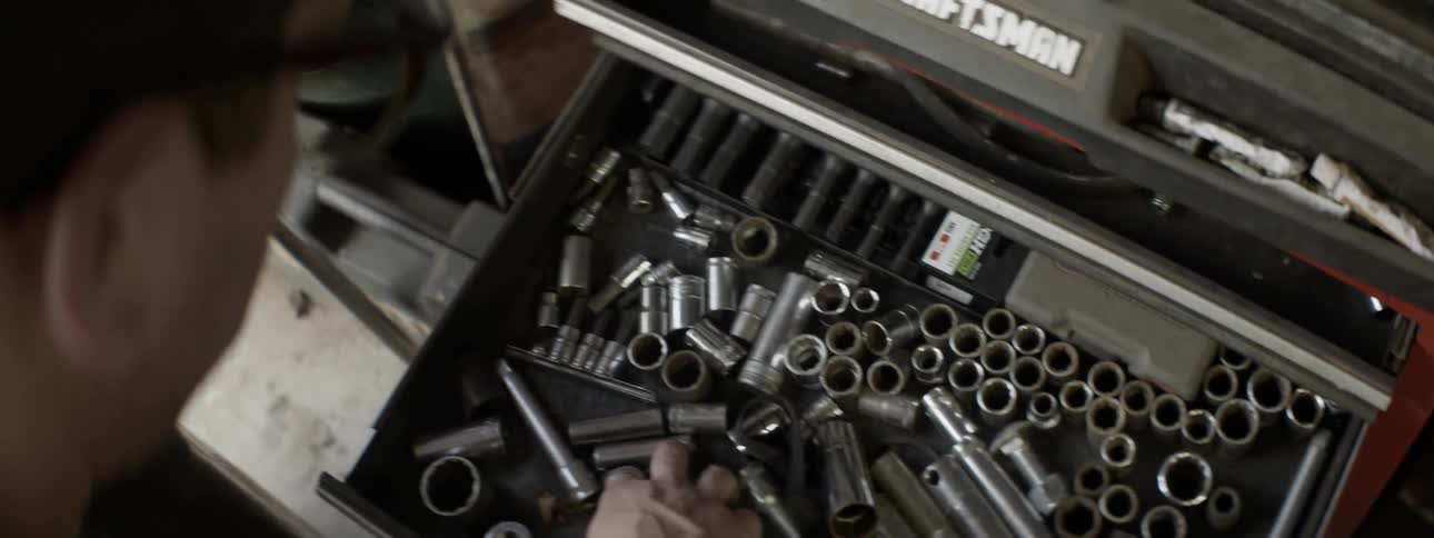 A mechanic searches for tools in a toolbox