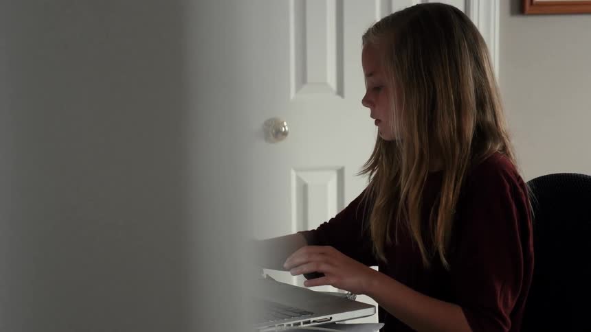 A girl is using her laptop in her bedroom
