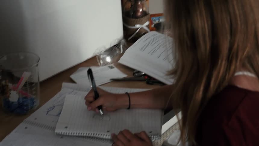 A young girl sketches in a notebook
