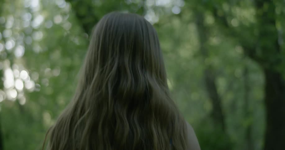 A young woman walks out in the woods