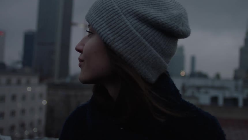 A woman in a beanie looks around