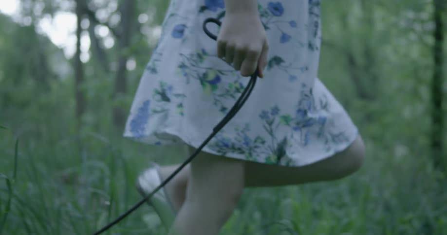 Girls wearing a dress and dragging a leash through high grass