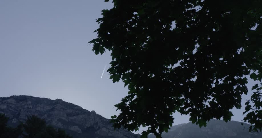 A plain leaves a chem trail in the sky over a natural setting
