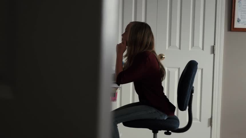 A young girl writes while sitting at a desk