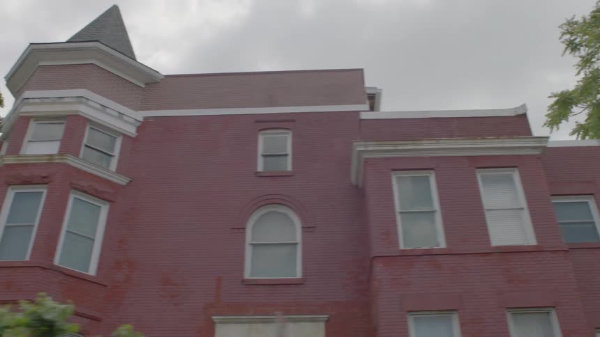A red buildings sits next to a city street on an overcast day
